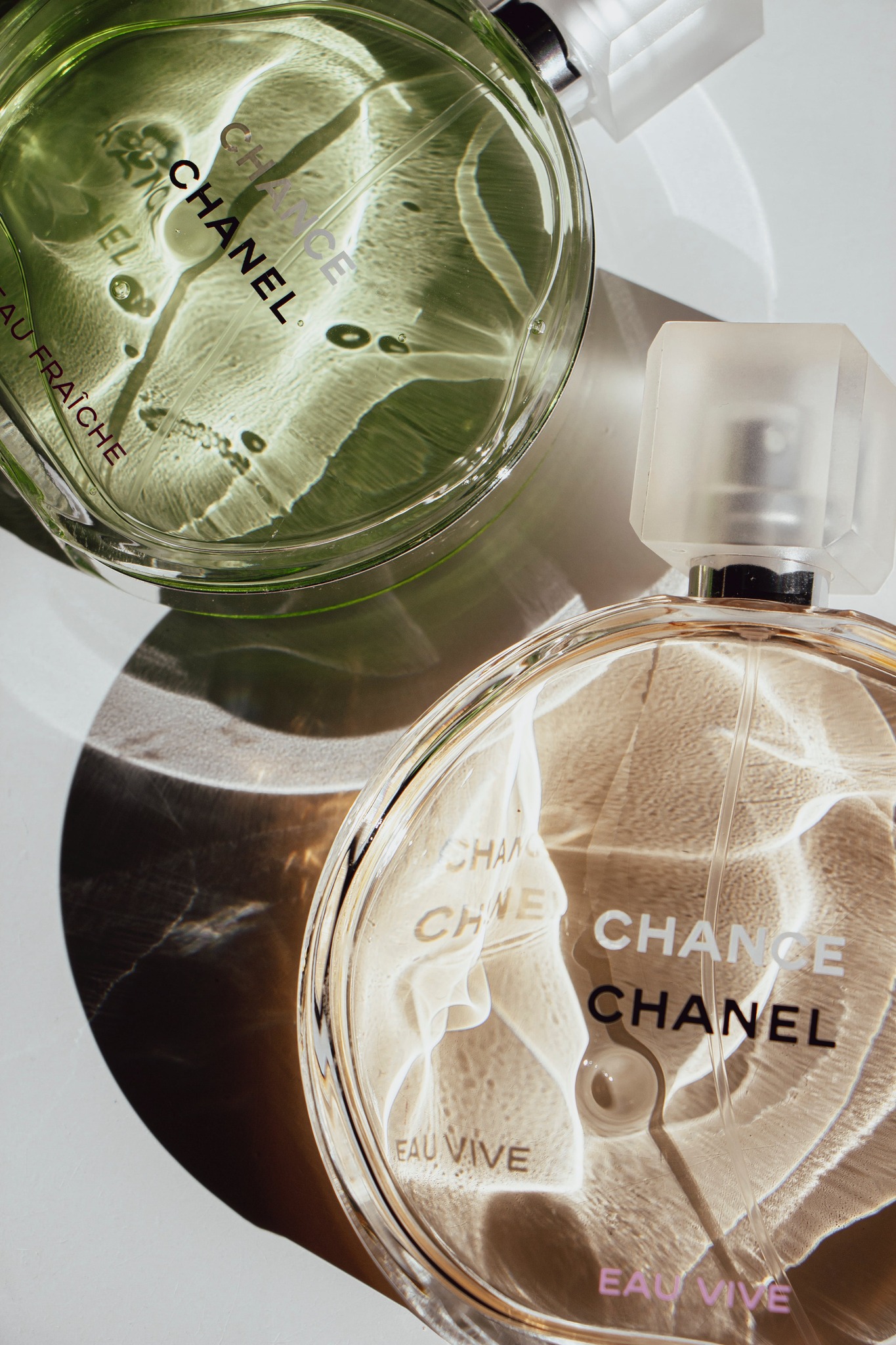 Bottles of Chanel perfume laying flat with light filtering through them