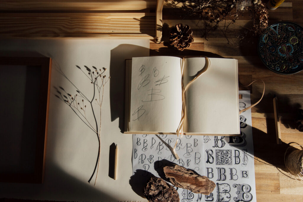 Sketch book and doodles laying flat on a wooden counter.